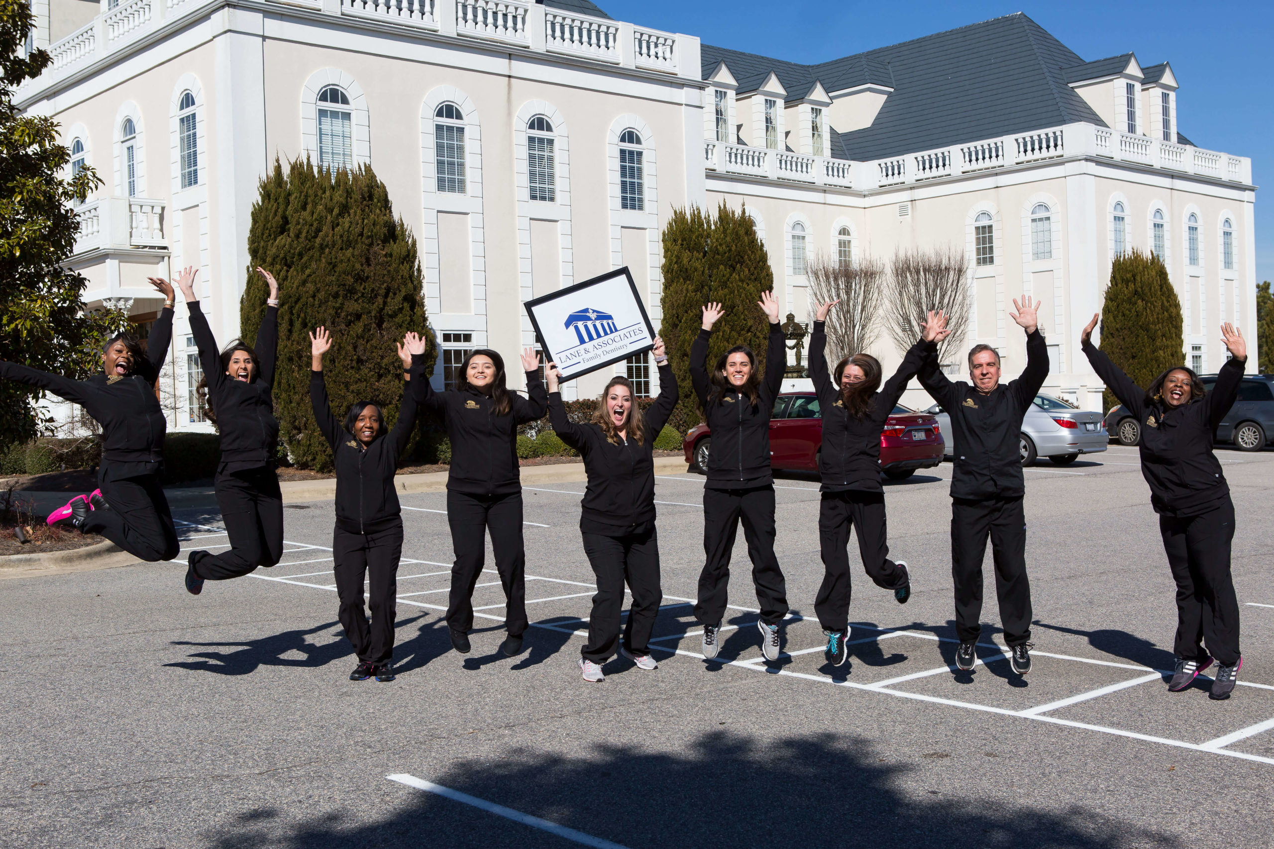 Dental staff in Garner jumping in front of building smiling big
