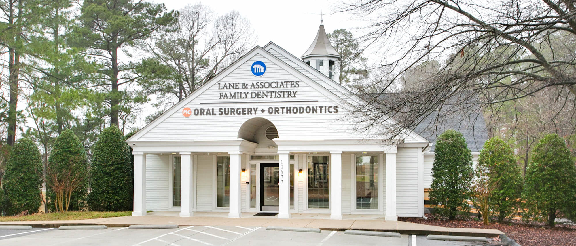 White building with triangular roof and columns and Lane DDS sign on front