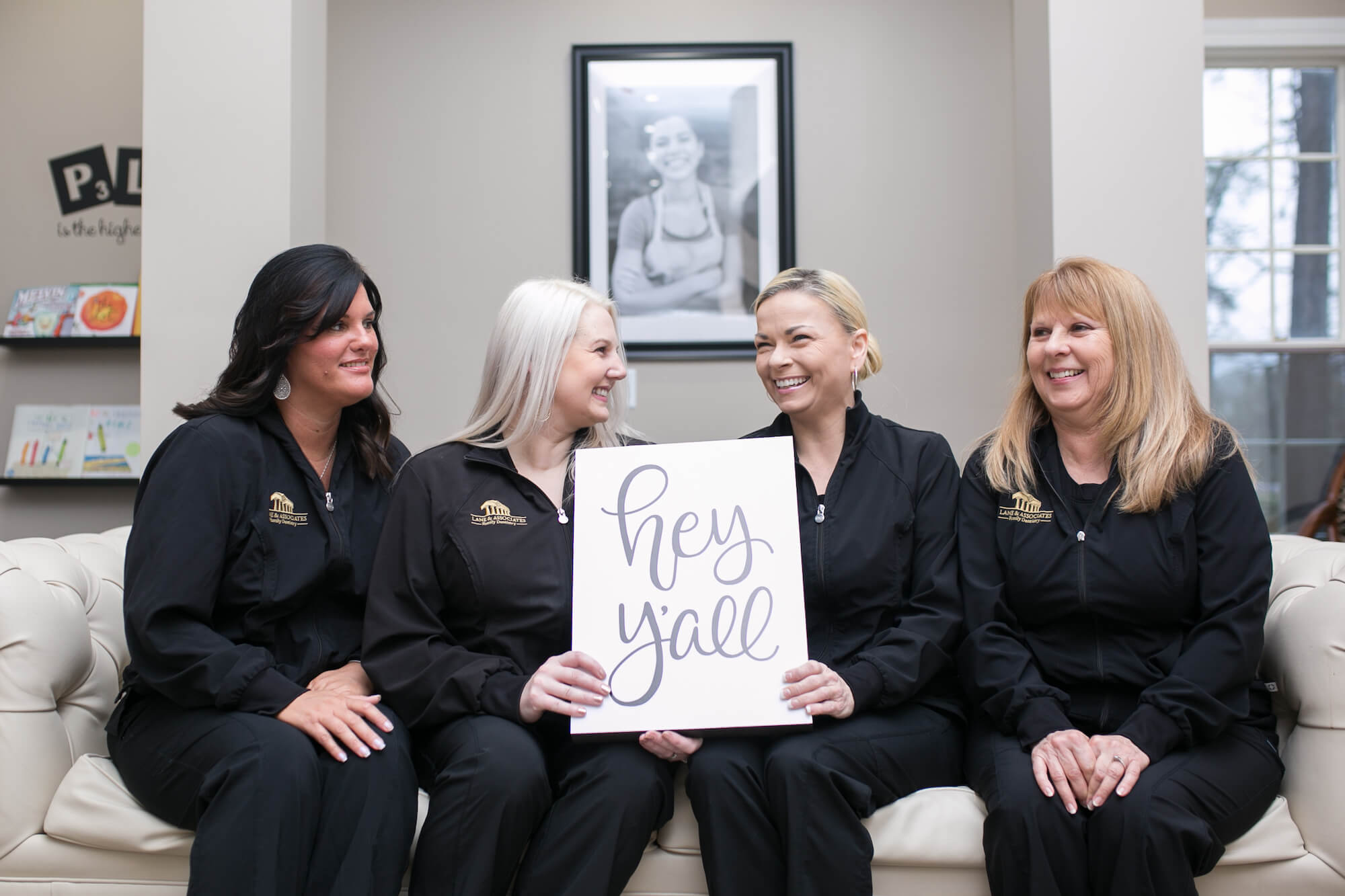 Southern Pines Dental staff holding sign that says "Hey y'all" laughing