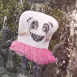 Tooth costume with eyes and mouth wearing a pink tutu