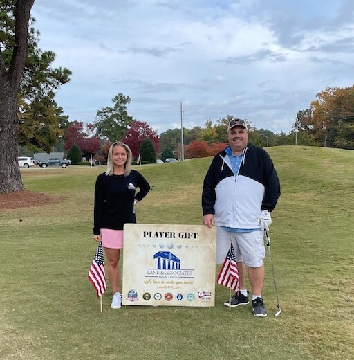 Employees at Golf Classic standing in front of Lane Sign