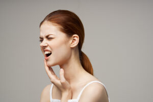 beautiful woman touching face with hand toothache red hair white t-shirt. High quality photo