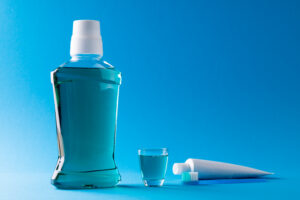 Image of mouthwash, toothbrush and toothpaste on blue surface. Health, dentistry, dental accessories and taking care of teeth concept.