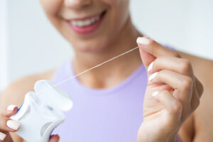 Portrait of beautiful woman cleaning teeth with dental floss.